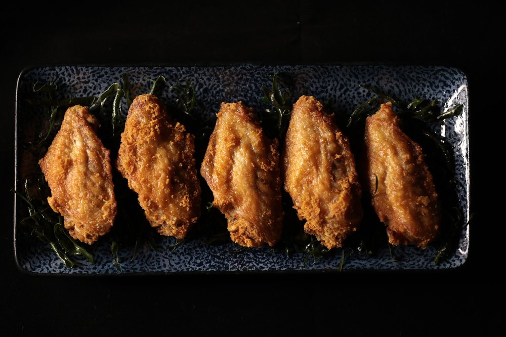 ปีกไก่ทอดกรอบเสิร์ฟบนจานหินสีเข้ม ที่ Owl's Nest Bar & Bistro